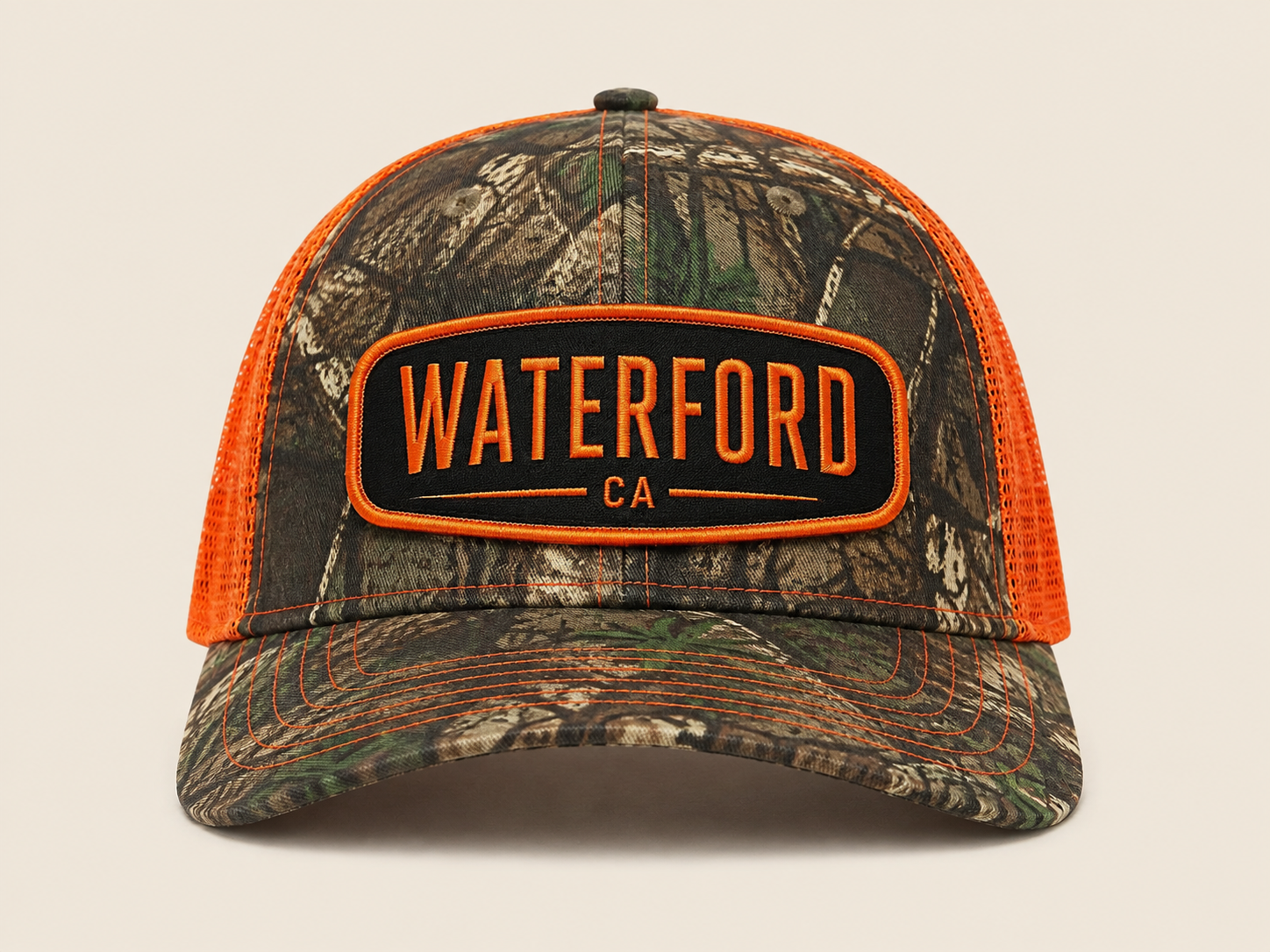Waterford Mossy Oak trucker hat with orange mesh and WATERFORD CA embroidered patch